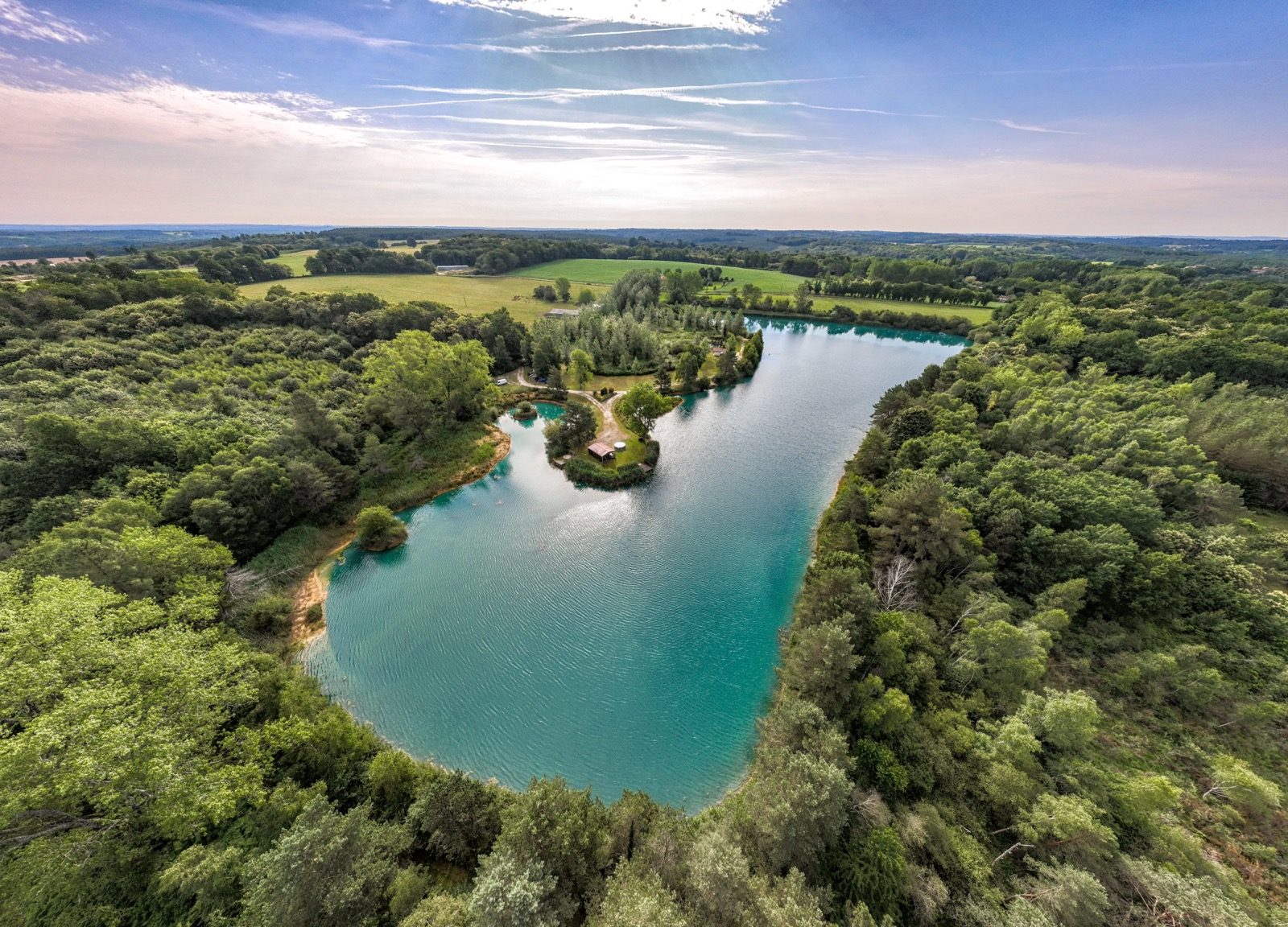 Aerial of turquoise lake winding through forest